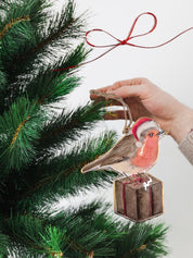 Festive tin Christmas decoration featuring a small robin wearing a Santa hat, complemented by a gift motif for added holiday spirit.